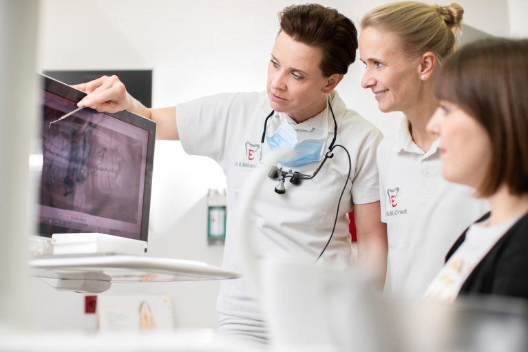Ärztinnen Dr. Mönnich und Dr. Dr. Orwat beraten Patientin an Röntgenbild