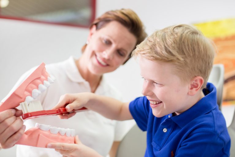 Dr. Verena Mönnich zeigt einem Kind wie man Zähne putzt