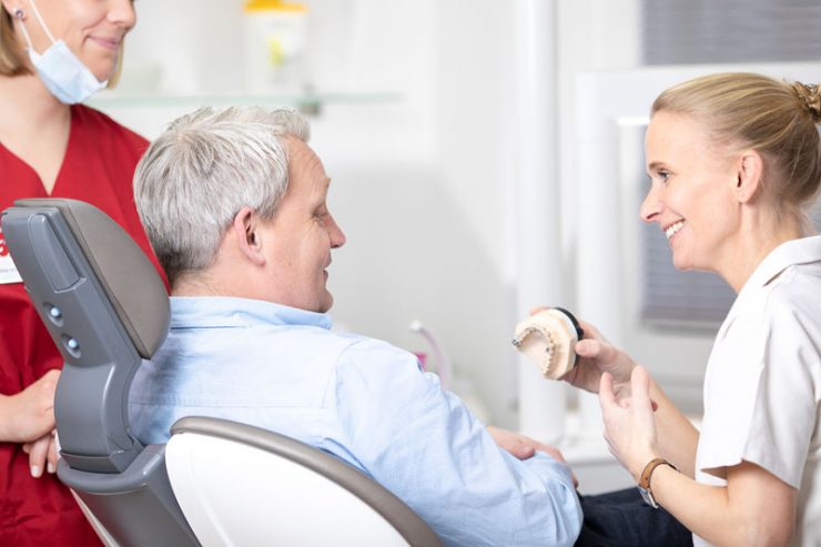 Dr. Melanie Orwat zeigt männlichem Patient Möglichkeiten für Zahnersatz auf